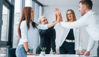 Project manager and scrum master inspiring happy Agile team members giving high five in an office