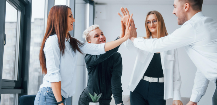 Project manager and scrum master inspiring happy Agile team members giving high five in an office
