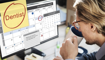 A man is learning how to sync google calendar with outlook calendar looking at a laptop while drinking coffee in an office with help of Easynote