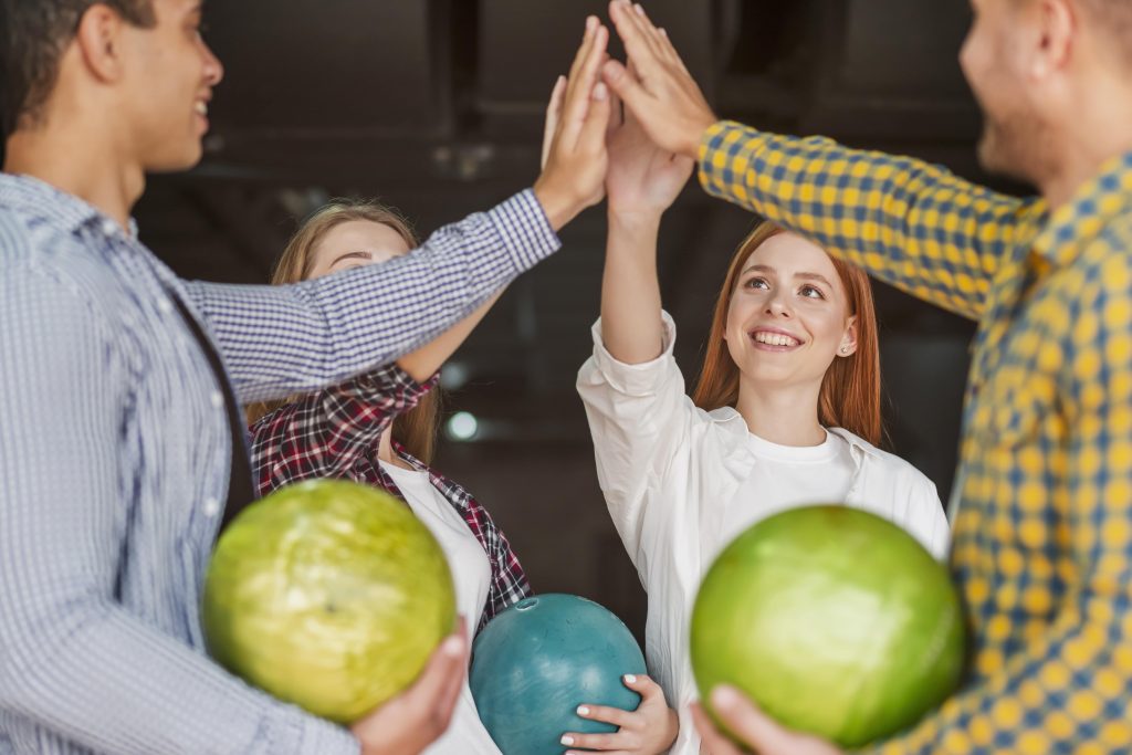 Collaboration works for your company when you build teamwork and it shows young team members playing with green balls in team building activity