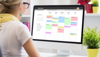 scheduling assistant shown on a screen and a businesswoman is looking at it in her office