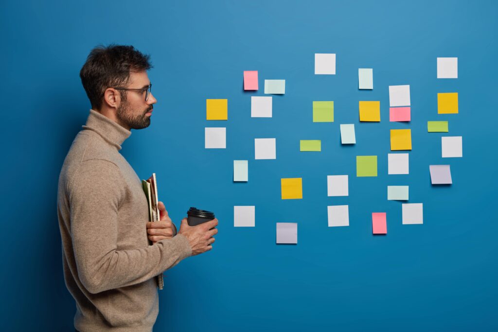 best planner for adhd used by a male standing in front of a blue wall using sticky notes 