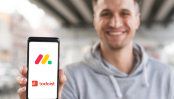 Monday vs Todoist comparison used to determine which tool is better shown on a phone held by a young businessman