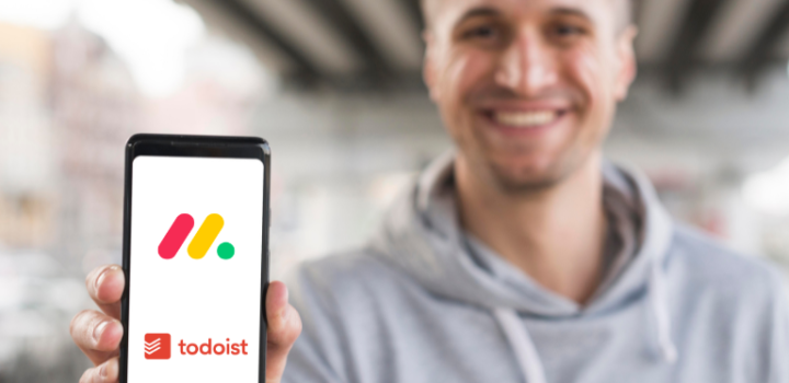 Monday vs Todoist comparison used to determine which tool is better shown on a phone held by a young businessman