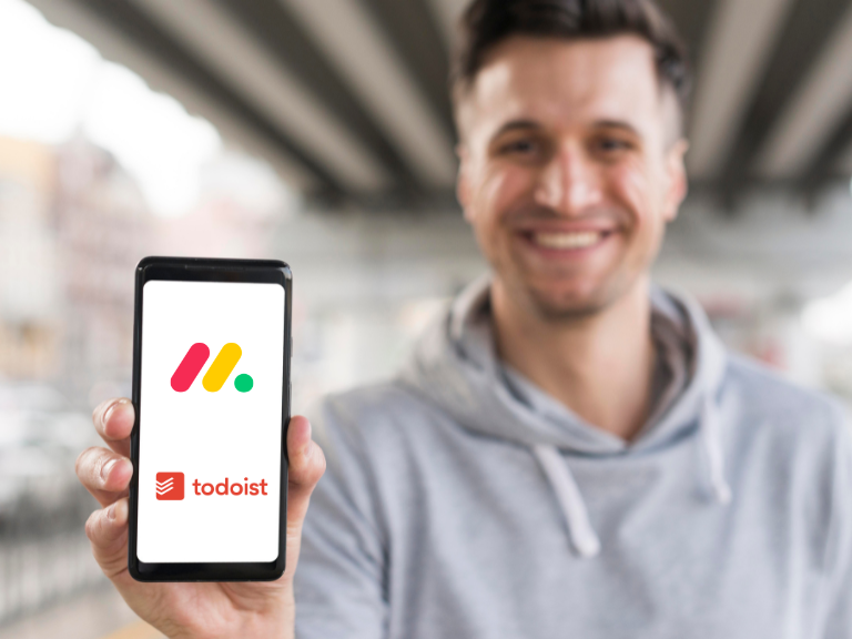 Monday vs Todoist comparison used to determine which tool is better shown on a phone held by a young businessman