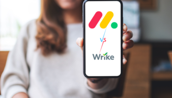 young businesswoman holding a monday vs wrie written on her phone showing the comparison between the two tools